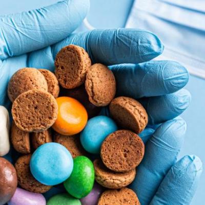 behandschuht Hände halten Süßigkeiten über medizinisches Material wie Masken